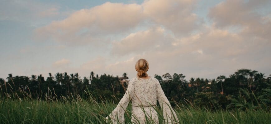 Young,Woman,In,Flown,White,Dress,Walking,Through,Tall,Grass